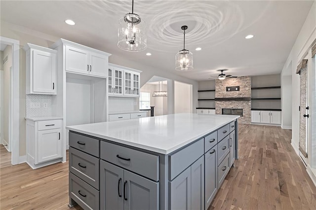 kitchen with a kitchen island, white cabinets, gray cabinets, and light wood finished floors
