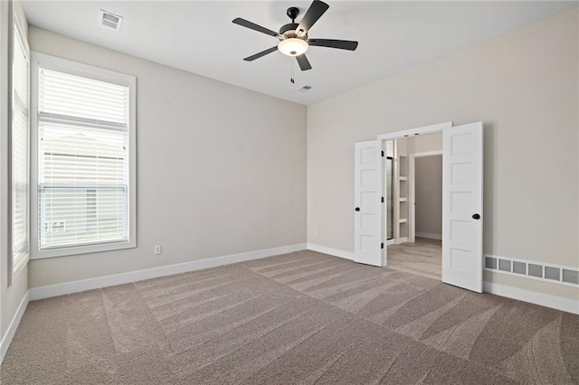 empty room featuring visible vents, baseboards, and carpet floors