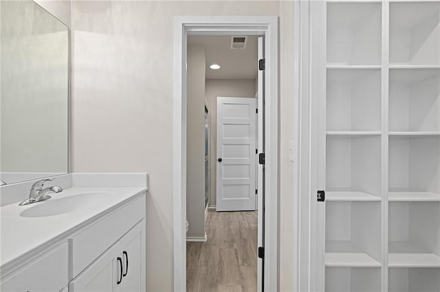 bathroom featuring visible vents, vanity, baseboards, and wood finished floors