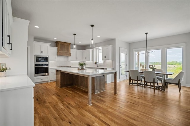 25010 W 142nd St, Olathe, KS 66061 - kitchen with appliances with stainless steel finishes, decorative backsplash, light wood-style flooring, a kitchen island, and light countertops