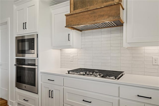 25010 W 142nd St, Olathe, KS 66061 - kitchen featuring appliances with stainless steel finishes, custom exhaust hood, light countertops, white cabinetry, and decorative backsplash