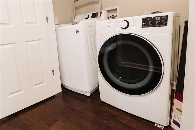 laundry room with washing machine and clothes dryer and dark wood-type flooring