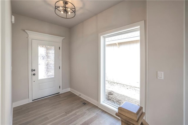 foyer featuring plenty of natural light, visible vents, baseboards, and light wood-style flooring