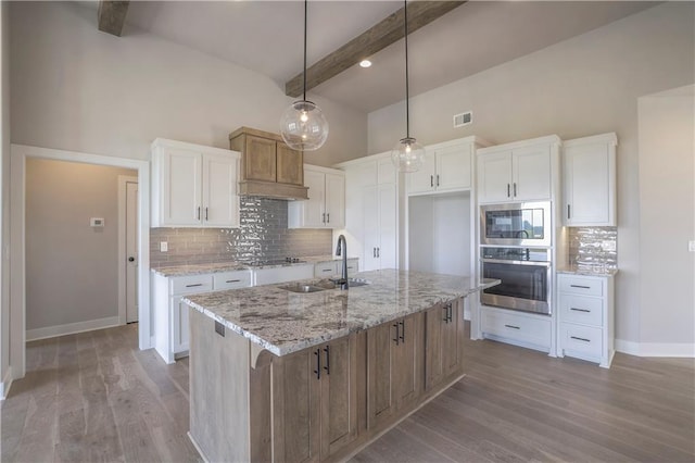 kitchen featuring visible vents, light wood-style flooring, appliances with stainless steel finishes, a sink, and beamed ceiling