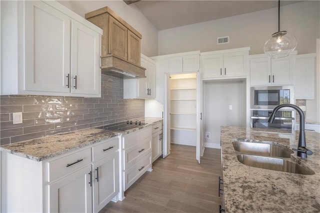 kitchen with light wood-style flooring, stainless steel appliances, a sink, visible vents, and tasteful backsplash