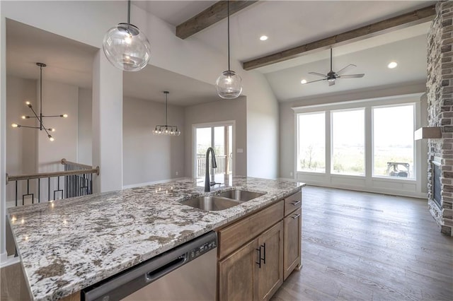 kitchen with a fireplace, a sink, open floor plan, stainless steel dishwasher, and light wood finished floors