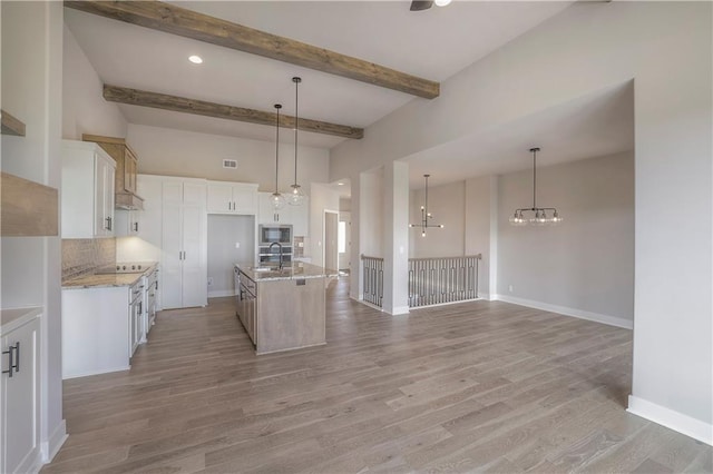 kitchen with light wood-style floors, stainless steel microwave, a sink, and decorative backsplash