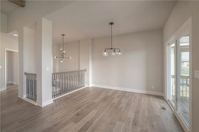 unfurnished room with light wood-type flooring, visible vents, baseboards, and an inviting chandelier