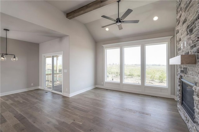 unfurnished living room featuring lofted ceiling with beams, dark wood-type flooring, a ceiling fan, a stone fireplace, and baseboards