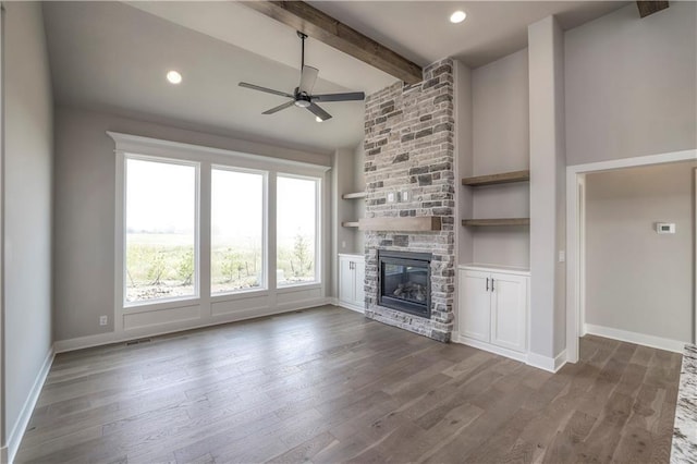 unfurnished living room with ceiling fan, vaulted ceiling with beams, a fireplace, baseboards, and dark wood finished floors