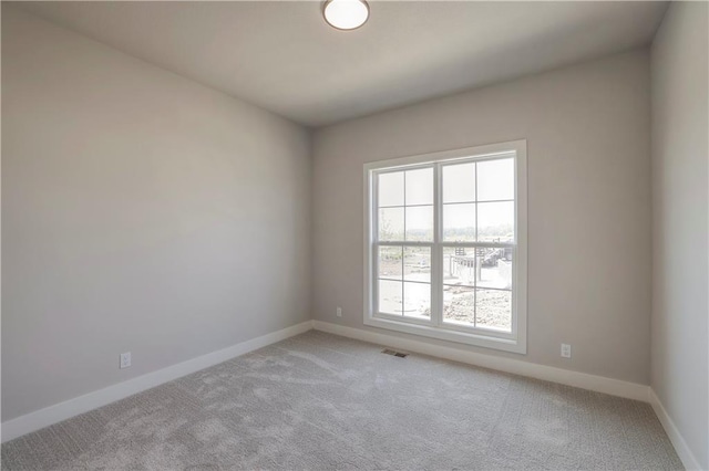 carpeted spare room featuring visible vents and baseboards