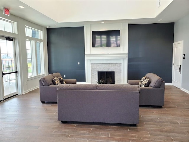 living room with recessed lighting, a brick fireplace, wood finished floors, and baseboards