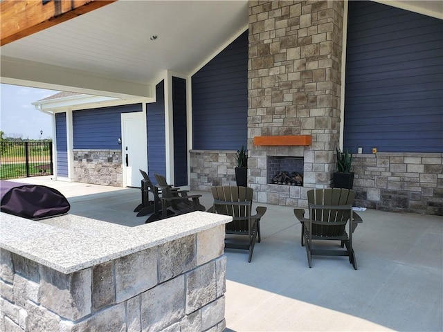 view of patio with fence and an outdoor stone fireplace