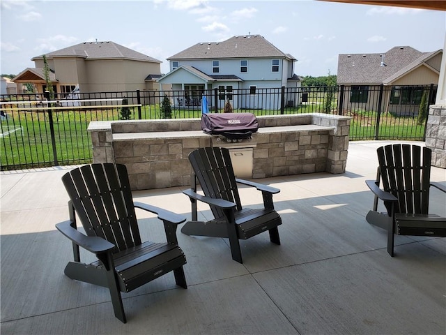 view of patio / terrace featuring a residential view, a fenced backyard, and an outdoor kitchen