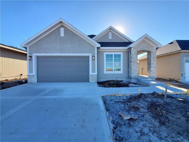 view of front facade with a garage, stone siding, driveway, and stucco siding