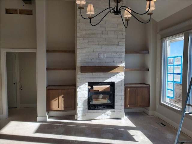 unfurnished living room featuring visible vents, baseboards, a notable chandelier, and a stone fireplace