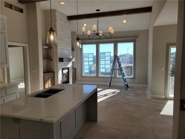 kitchen featuring a towering ceiling, baseboards, beamed ceiling, an inviting chandelier, and pendant lighting