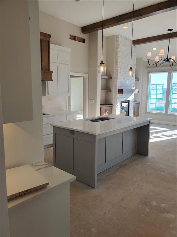 kitchen featuring a kitchen island, white cabinets, light countertops, hanging light fixtures, and beamed ceiling