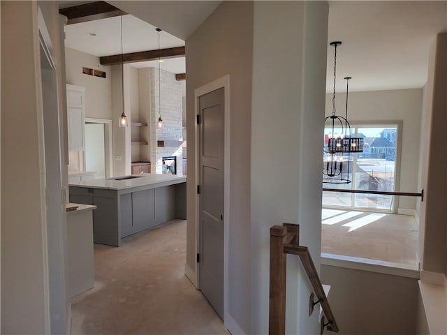 hall with a notable chandelier, beamed ceiling, an upstairs landing, and unfinished concrete floors