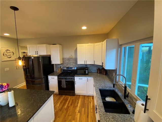 kitchen featuring black appliances, light hardwood / wood-style floors, hanging light fixtures, sink, and white cabinetry