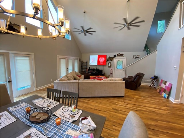 living room featuring ceiling fan with notable chandelier, high vaulted ceiling, and hardwood / wood-style flooring