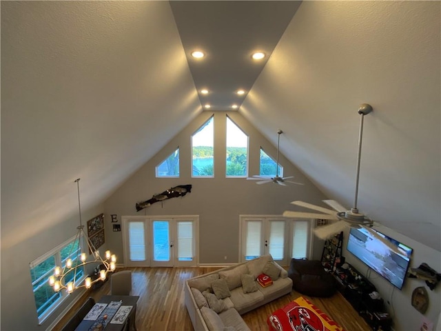 unfurnished living room with ceiling fan with notable chandelier, french doors, vaulted ceiling, and wood-type flooring