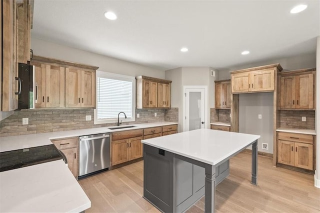 kitchen with a breakfast bar, dishwasher, sink, a center island, and light hardwood / wood-style flooring