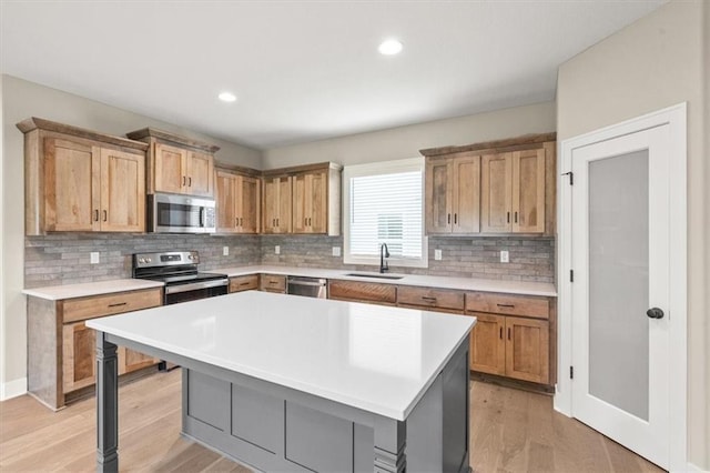 kitchen with appliances with stainless steel finishes, light hardwood / wood-style floors, a kitchen island, and backsplash