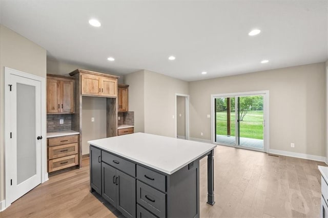 kitchen featuring tasteful backsplash, gray cabinets, light hardwood / wood-style floors, and a center island