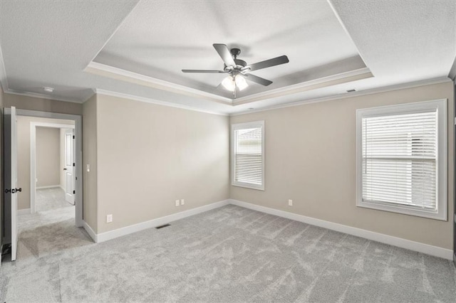 carpeted empty room with ceiling fan, ornamental molding, a tray ceiling, and a textured ceiling