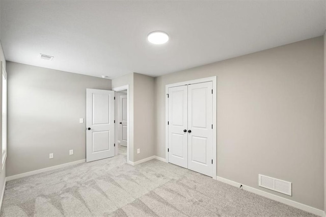 unfurnished bedroom featuring light carpet and a closet