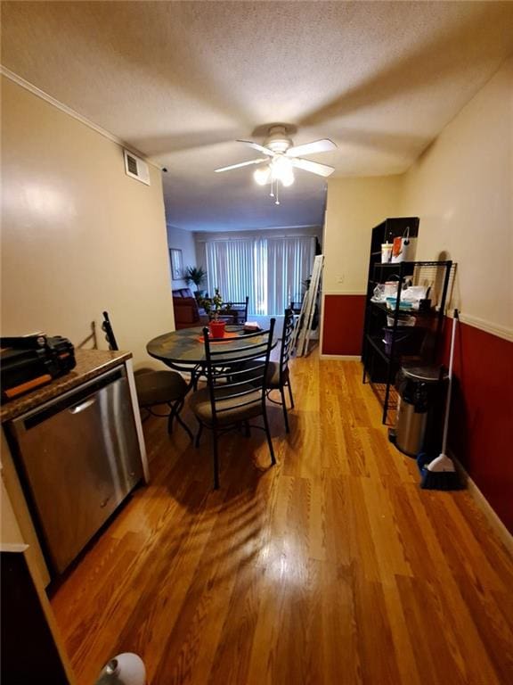 dining area with light wood-style flooring, a ceiling fan, visible vents, and a textured ceiling