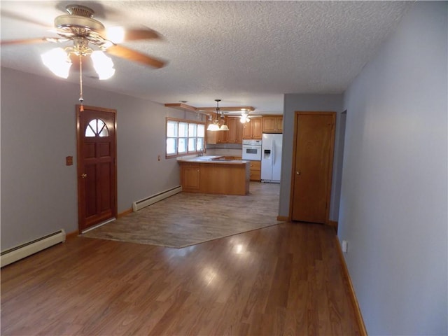 kitchen with baseboard heating, a peninsula, ceiling fan, and white fridge with ice dispenser