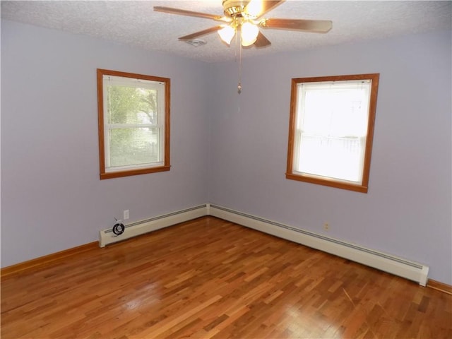 spare room featuring ceiling fan, baseboard heating, hardwood / wood-style floors, and a textured ceiling