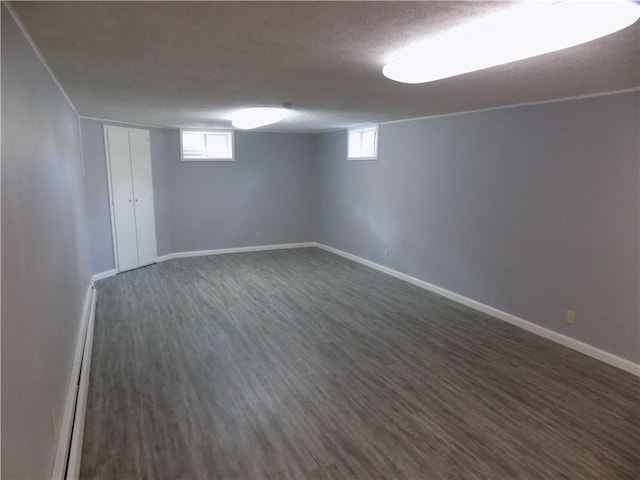 below grade area featuring plenty of natural light, dark wood-type flooring, and baseboards