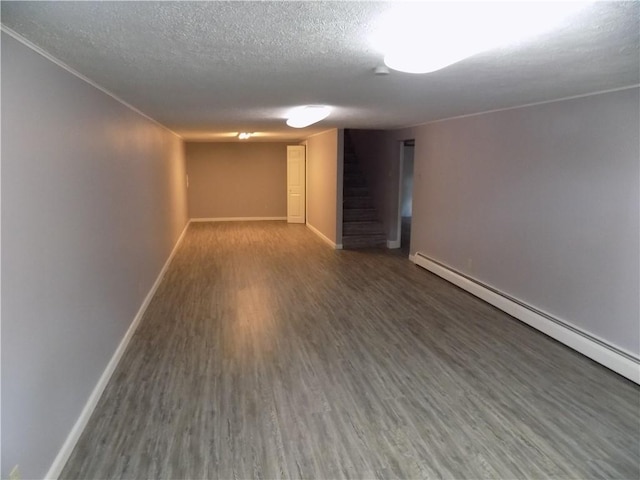 basement with a textured ceiling, baseboard heating, and dark hardwood / wood-style flooring