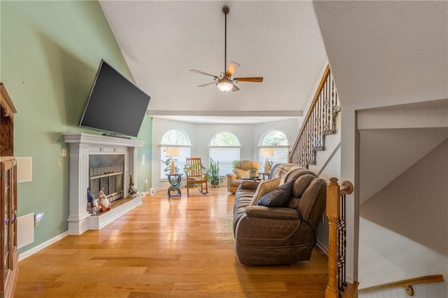 living room featuring a towering ceiling, light hardwood / wood-style flooring, and ceiling fan