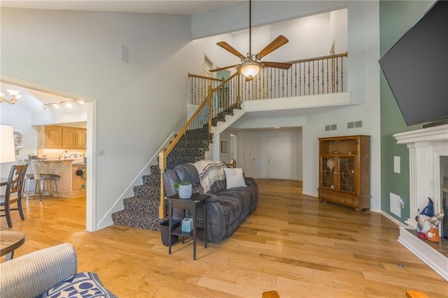 living room with high vaulted ceiling, light wood-type flooring, and ceiling fan with notable chandelier