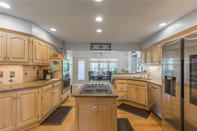 kitchen featuring a kitchen island, appliances with stainless steel finishes, light brown cabinetry, light hardwood / wood-style flooring, and sink