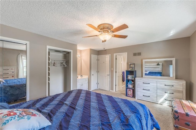 bedroom with connected bathroom, ceiling fan, a textured ceiling, and two closets