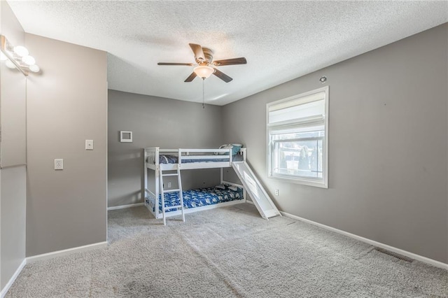 unfurnished bedroom with carpet floors, a textured ceiling, and ceiling fan