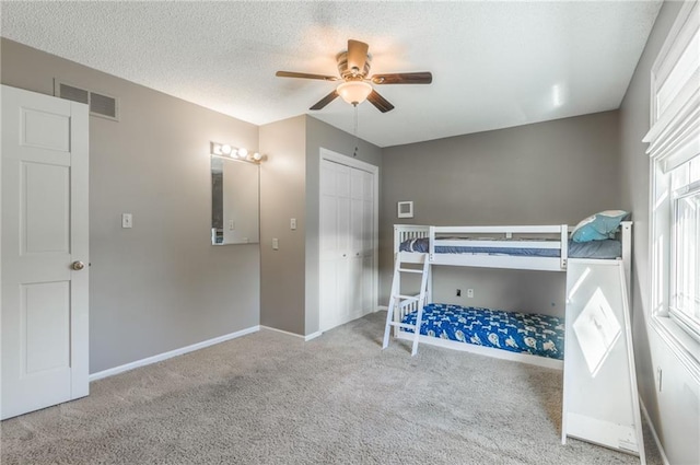 unfurnished bedroom with a closet, multiple windows, light colored carpet, and ceiling fan