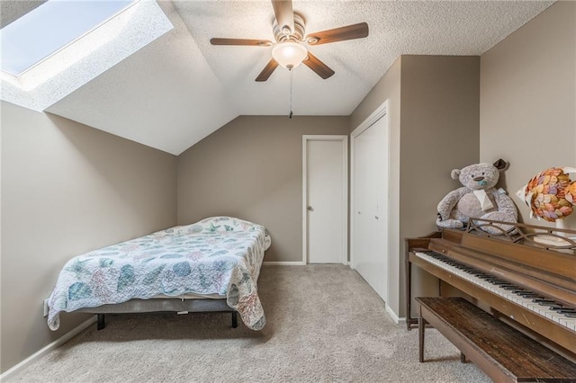 bedroom featuring a textured ceiling, a closet, ceiling fan, light carpet, and lofted ceiling with skylight