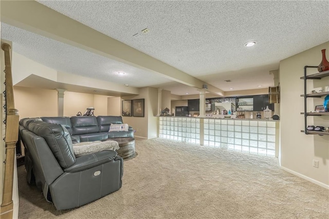 living room featuring decorative columns, carpet, and a textured ceiling