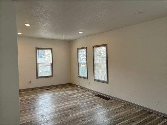 spare room with light wood-type flooring and a textured ceiling