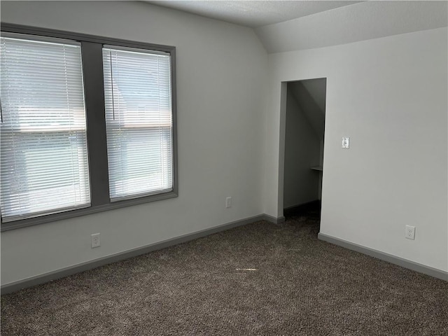 carpeted spare room with vaulted ceiling