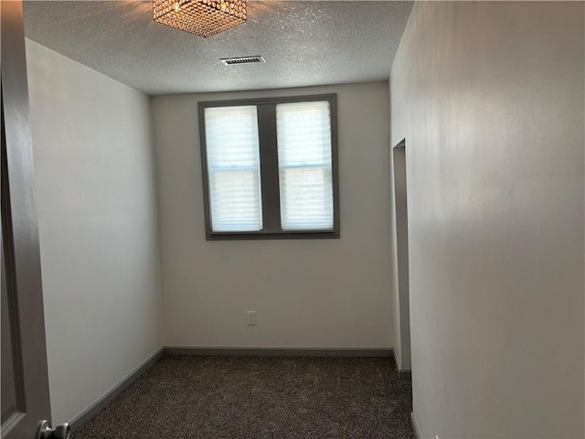 spare room with dark colored carpet and a textured ceiling