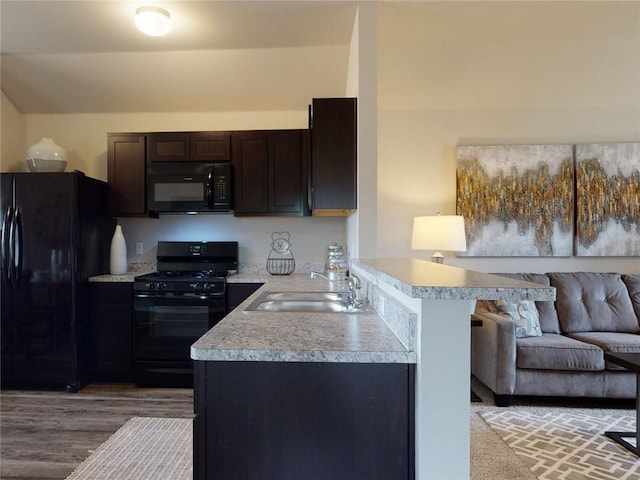 kitchen featuring black appliances, kitchen peninsula, sink, hardwood / wood-style flooring, and dark brown cabinetry