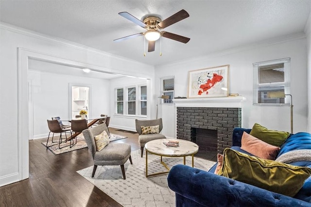 living room featuring a textured ceiling, a fireplace, dark hardwood / wood-style flooring, ornamental molding, and ceiling fan