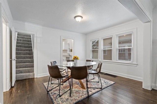 dining area featuring a textured ceiling, dark hardwood / wood-style floors, ornamental molding, and sink